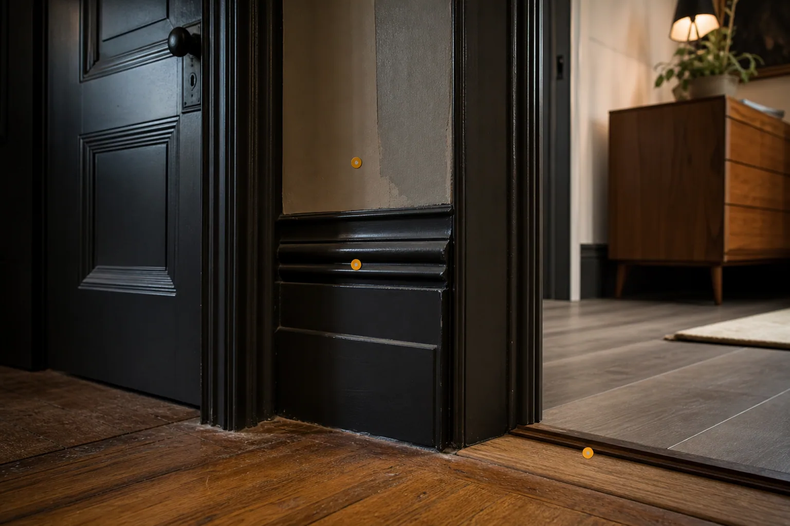 Older painted doorway trim and updated flooring transition with amber markers for previous work and material matching.